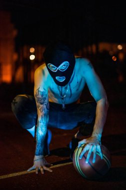 Kar maskeli genç adam kamera suçuna ve şiddete bakıyor, uyuşturucu, moda, rap, rapçi yeni okul, gece kentinde tarz.