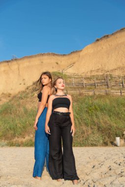 Kumsalda koşan ve yaz tatilinin tadını çıkaran mutlu gençler. Sahilde yürüyen iki güzel kız.