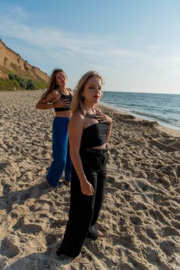 Kumsalda koşan ve yaz tatilinin tadını çıkaran mutlu gençler. Sahilde yürüyen iki güzel kız.