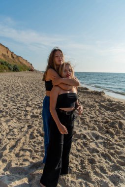 Kumsalda koşan ve yaz tatilinin tadını çıkaran mutlu gençler. Sahilde yürüyen iki güzel kız.