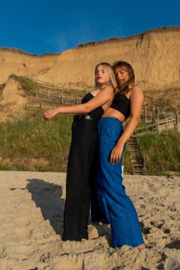 Kumsalda koşan ve yaz tatilinin tadını çıkaran mutlu gençler. Sahilde yürüyen iki güzel kız.