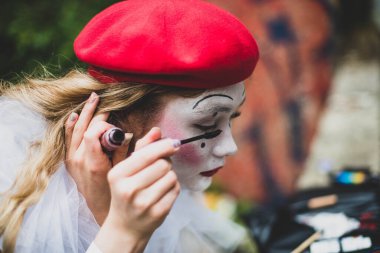 Pandomimci kız. Doğaçlama. Cadılar Bayramı için uygun. Pandomim farklı duygular gösterir. Üzgün palyaço. Bir kadın pandomimci yüzünü boyuyor..