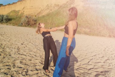 Kumsalda koşan ve yaz tatilinin tadını çıkaran mutlu gençler. Sahilde yürüyen iki güzel kız.