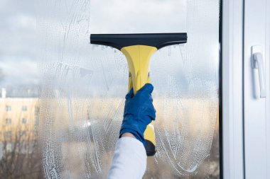 Elektrikli süpürgeyle el temizliği. Kadınlar ellerinde özel temizleme cihazı olan mavi eldivenleri eve teslim ederler, ekipmanlara yakın çekim yaparlar..