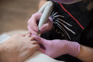 A nail cuticle disposal. A machine pedicure for a girl at the beauty salon. Pedicurist using an electrical treatment.	