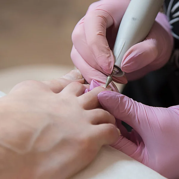 Güzellik uzmanı güzellik salonunda bir kadın için pedikür yapıyor. Pedikürcü elektrikli çivi matkabı kullanıyor. Güzellik ve sağlık kavramı