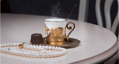 Masada altın kahve fincanı ve inci mücevher. Lüks bir zarafet konsepti.