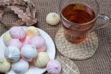 Ev yapımı kremalı öpücükler ve çay fincanı. Doğal çuval bezi arka planında kremalı kurabiye.. 