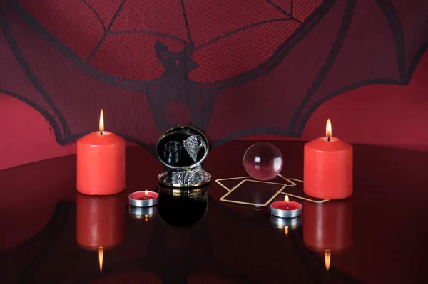 Candles, mirror, rings and tarot cards on black background. Divination still life by candlelight in the evening. Magic ritual. Mystical atmosphere of fortune telling. Esoteric concept.