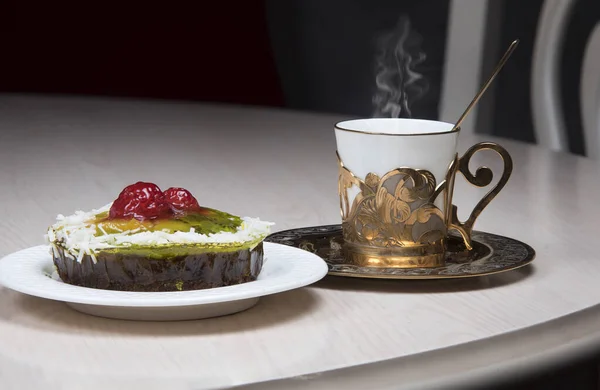 Golden coffee cup and berry tartlet or fruits cake on table in cafe, luxurious elegance style concept.