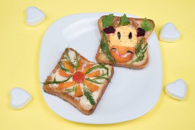 Yenilebilir inek boğalı sandviç ve sarı arka planda çiçek. Çocuklar için gıda sanatı fikri. Çocuğun kahvaltısı..