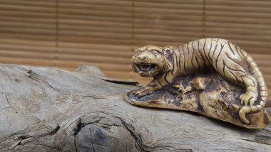 Japon netsuke figürünün ahşap ve bambu arka plandaki yakın çekimi. Kaplan maskotu heykeli