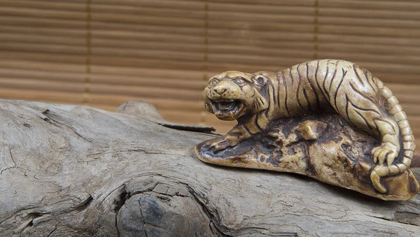 Japon netsuke figürünün ahşap ve bambu arka plandaki yakın çekimi. Kaplan maskotu heykeli