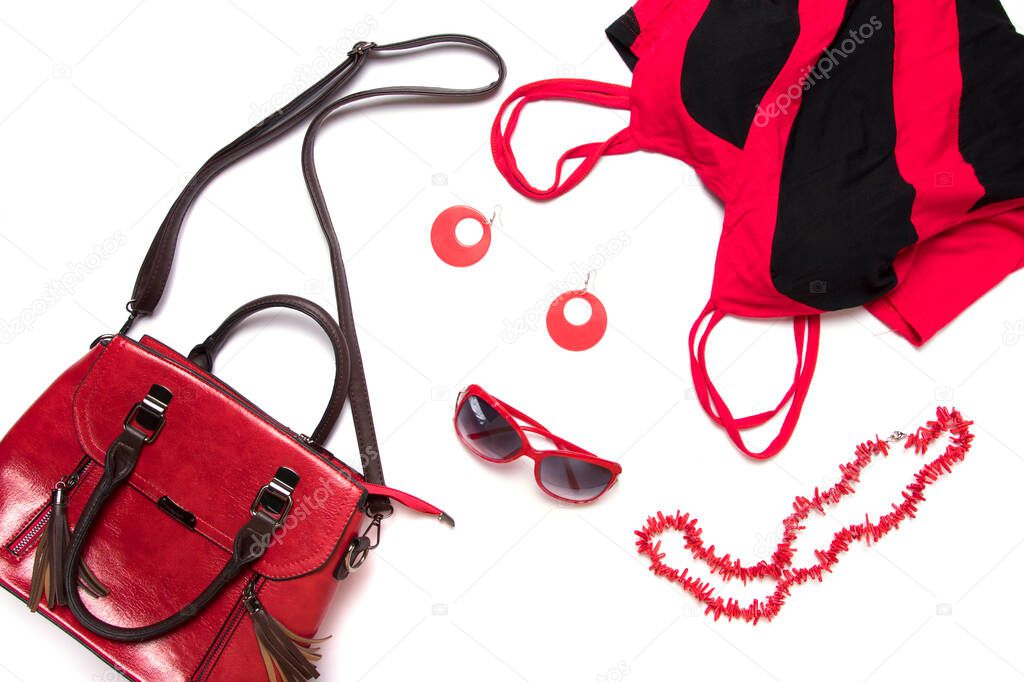 Top view or flat lay of female clothes and accessories collage, red women's handbag, glasses, blouse and necklace isolated on white background.