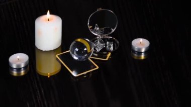Tarot kartlarıyla sihirli seanslar, beyaz mumlar, siyah arka planda yüzük ve ayna. Gizemli falcılık. Sihirli atmosfer.