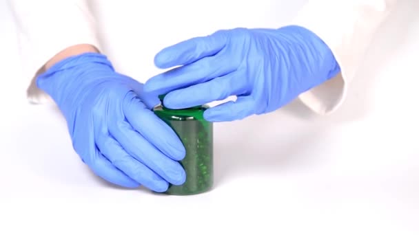 医師は手を手袋黄色の食品サプリメント油充填カプセルと医療用ボトルを開きます 薬が腕に注ぐ 白地だ コロナウイルスの概念保護 — ストック動画