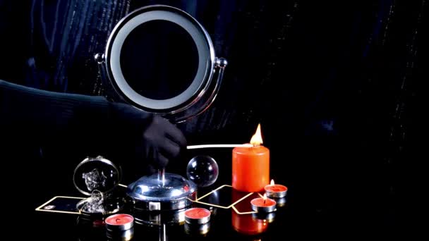 Fortunetellerova černá ruka v rukavicích hořela svíčkami. Připravuje se na spirituální rituál. Svíčky, zrcadlo, taro vozík a prsteny v tmavé místnosti. — Stock video