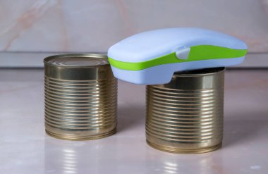 Electric can opener and canned goods on kitchen table clipart