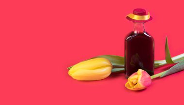 Kırmızı arka planda lale çiçekleri ve şapkalı küçük şarap şişesi. Alkol satışı kavramı