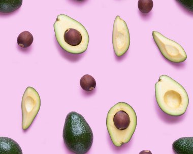 Avokado pürüzsüz desen. Avokado, avacado parçaları ve tohumlardan oluşan düz bir yer. Pembe arka planda izole edilmiş avokado parçalarından yapılan arkaplan.