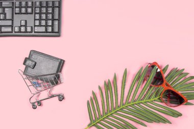 Düz klavye kolajı, alışveriş arabasında kart sahibi, sarı arka planda güneş gözlüğü ve palmiye yaprağı vardı. Seyahat blogu tasarımı. Üst görünüm, alanı kopyala