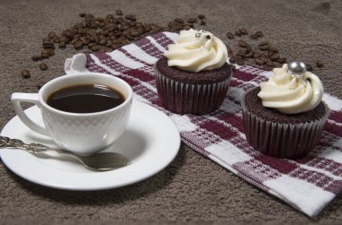 Kumaş arka planda iki kek, beyaz kahve fincanı, kremalı ev yapımı kek ve kavrulmuş kahve çekirdeği. Seçici odak.