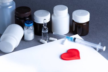 Kırmızı kalp sembolü, tıbbi şişeler, ilaçlar, aşı ve metnin için kağıtlar. Dünya Kalp Günü. Kalp hastalıkları.