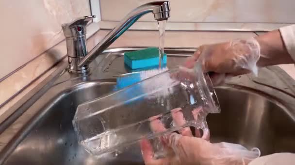 4K妇女在厨房水池里洗玻璃壶 靠近水罐 水龙头和戴手套的女性手 棕色背景 — 图库视频影像