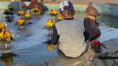 Şehrin çeşmesinde oturan ve oynayan bir çocuğun arkası. Şehir manzarası