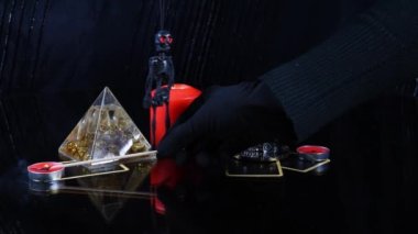 Falcının siyah eldivenli eli mum yakıyor. Ruhanilik ayinine hazırlanıyorum. Mumlar, ayna, taro arabası ve yüzükler karanlık odada. Fal bakmanın mistik atmosferi.
