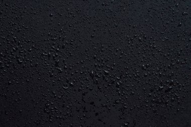 Su damlaları siyah cam arka planda izole edilmiş. Yağmur dokusu