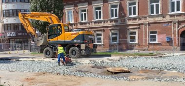 İnşaat alanı yeni asfalt yol kaldırımları, yol inşaat işçileri ve yol yapım makineleri sahnesi inşa ediyor. Perm, Rusya, 10 Ağustos 2021