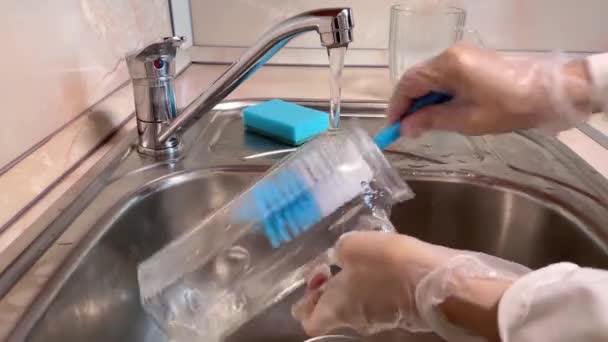 在厨房的水槽里洗玻璃壶 靠近水罐 水龙头和戴手套的女性手 棕色背景 — 图库视频影像
