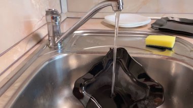 Mutfak lavabosunda siyah tabak yıkamak. Musluğu kapat.