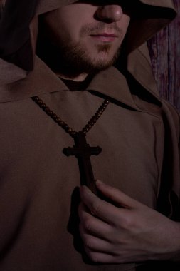 Ortaçağ keşişi kollarında tahta haçla gözleri kapalı dua ediyor.