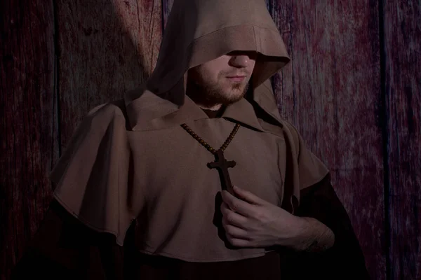 Средневековый монах молится с закрытыми глазами, с деревянным крестом в руках Стоковое Фото