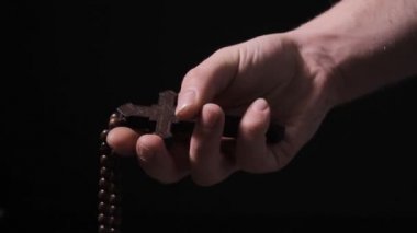 Bir adam elinde ahşap bir Hıristiyan haçı sıkar.