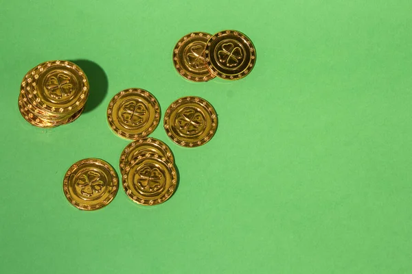 Aziz Patrick Günü altın sikkeleri yeşil arka planda yonca ile