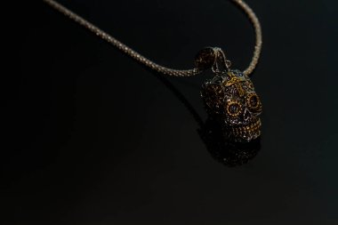 Meksika usulü siyah arka planda insan kafatasına sahip bir kolye. Gotik mücevherler.