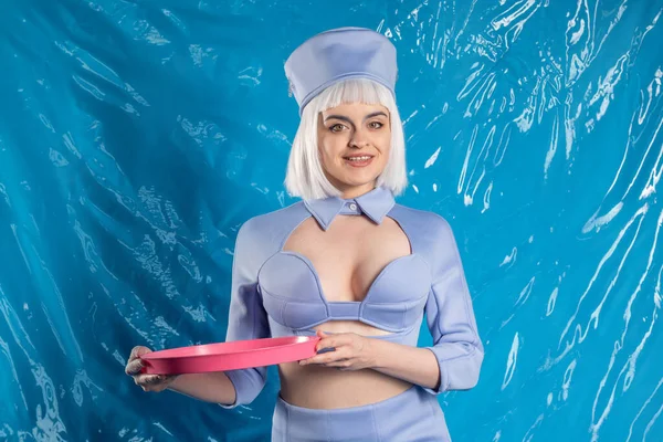 Mavi lateks arka planda mavi üniformalı hoş bir hostes.