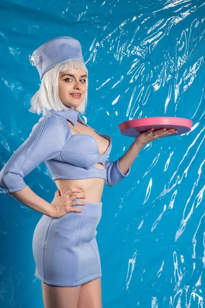 Mavi lateks arka planda mavi üniformalı hoş bir hostes.