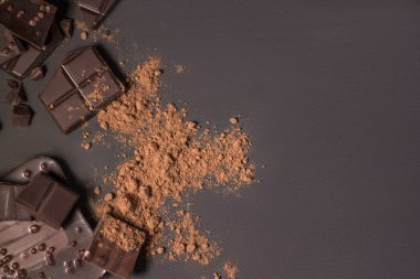 Çubuk ve farklı süt ve koyu çikolata parçalarının bileşimi, siyah arka plan görünümlü rendelenmiş kakao yakın plan.