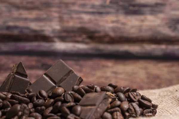 Tahta bir arka planda kahve çekirdekli çikolata yığını, fotokopi alanı yatay.