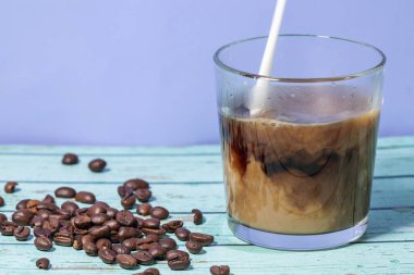 Süt mavi arka planda buzlu kahve bardağına dökülür.