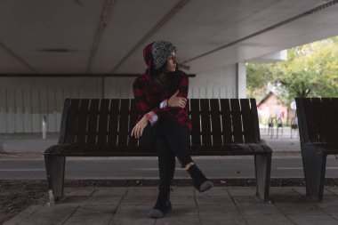 Depresyondaki genç evsiz kız ya da kadın köprünün altındaki bankta tek başına oturuyor. Yalnız ve endişeli karanlık görüntü seçici odaklanıyor.