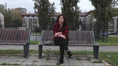 Depresyonda olan evsiz bir kız ya da şapkalı bir kadın sokağın ortasında tek başına oturuyor. Ümitsiz ve endişeli bir şekilde odaklanıyor.