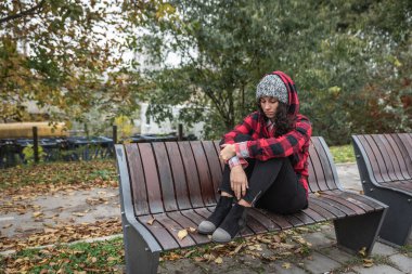 Depresyonda olan evsiz bir kız ya da şapkalı bir kadın sokağın ortasında tek başına oturuyor. Ümitsiz ve endişeli bir şekilde odaklanıyor.