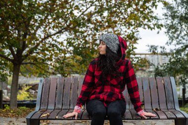 Depresyonda olan evsiz bir kız ya da şapkalı bir kadın sokağın ortasında tek başına oturuyor. Ümitsiz ve endişeli bir şekilde odaklanıyor.