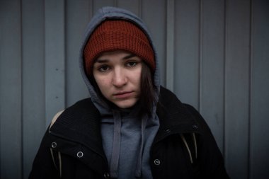 Çok genç, aç ve korkmuş evsiz genç kız soğuk kış gününde şehir sokaklarında tek başına dikiliyor. Gerçek insanlar seçici odaklanıyor.