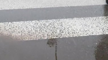 Yaya geçidinde ıslak asfalt yolda yürüyen ilk kişi ve kameralı çamur. 